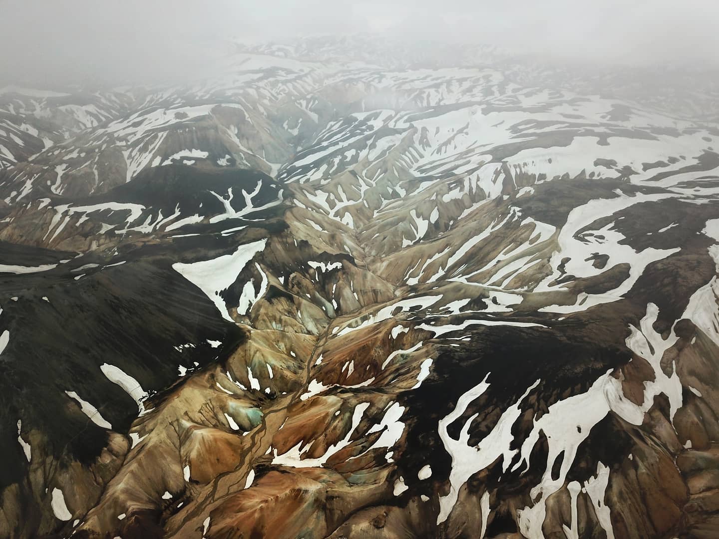 Aerial view of braided glacial rivers cutting through ochre highlands
