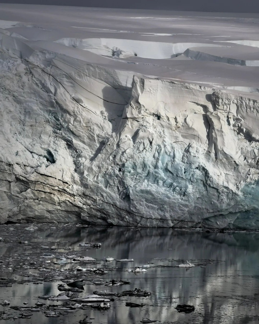 The blue-white face of a glacier meeting still meltwater