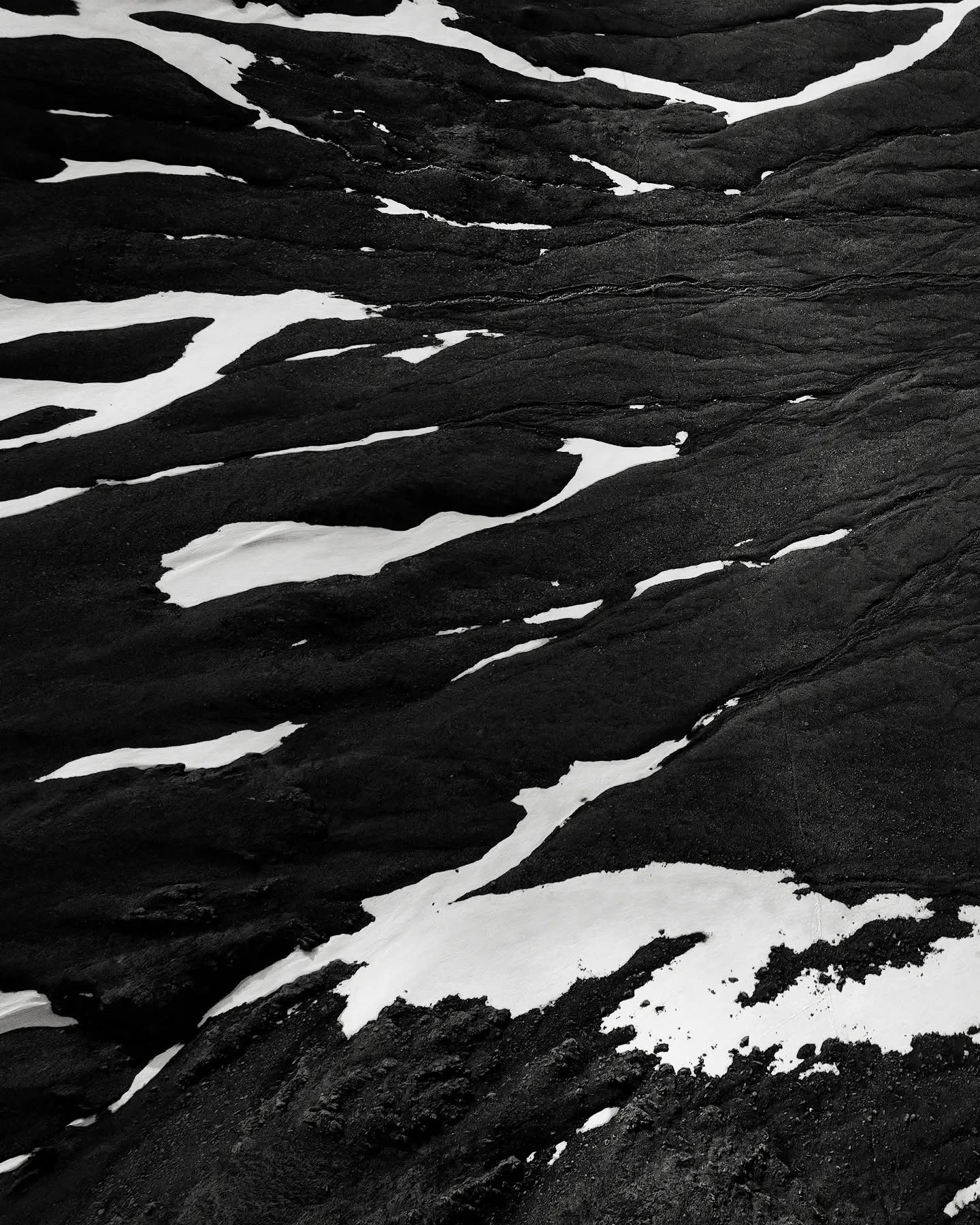 Snow patches marooned on black volcanic ground