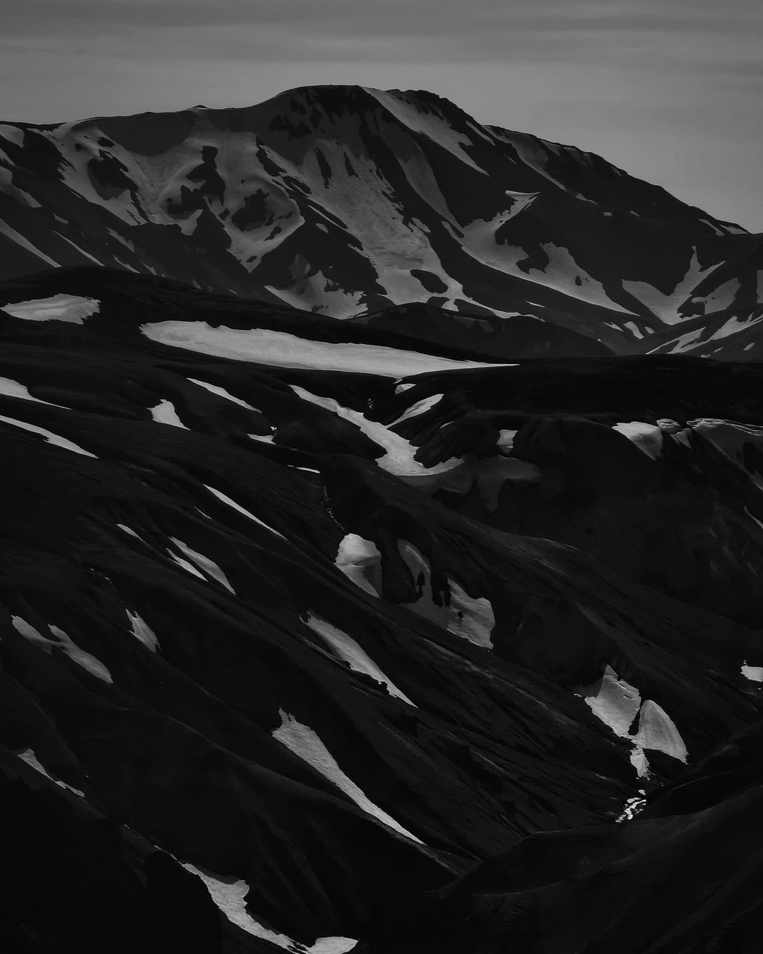 Snow patches scattered across dark volcanic slopes