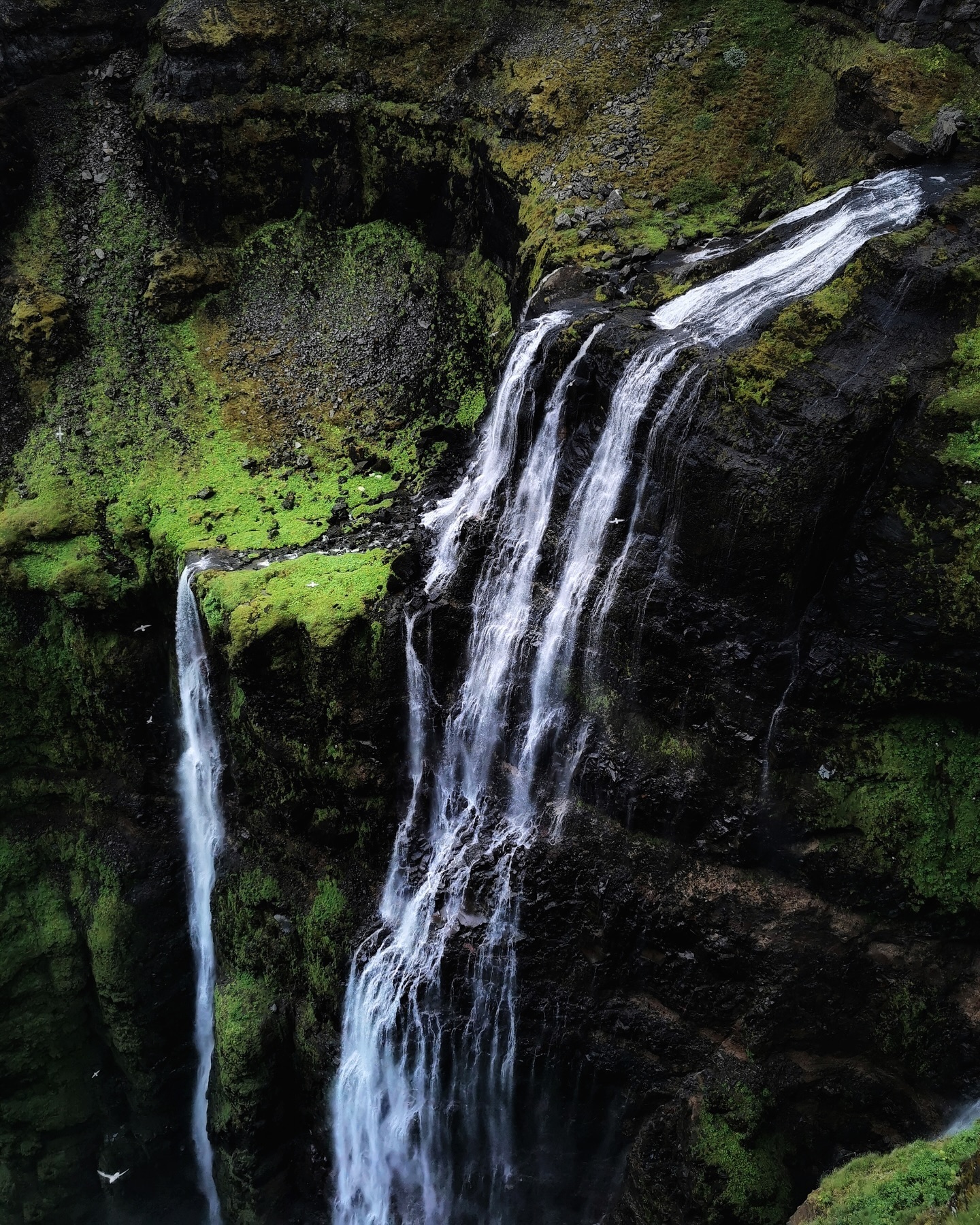 A tall waterfall dropping over a moss-covered cliff