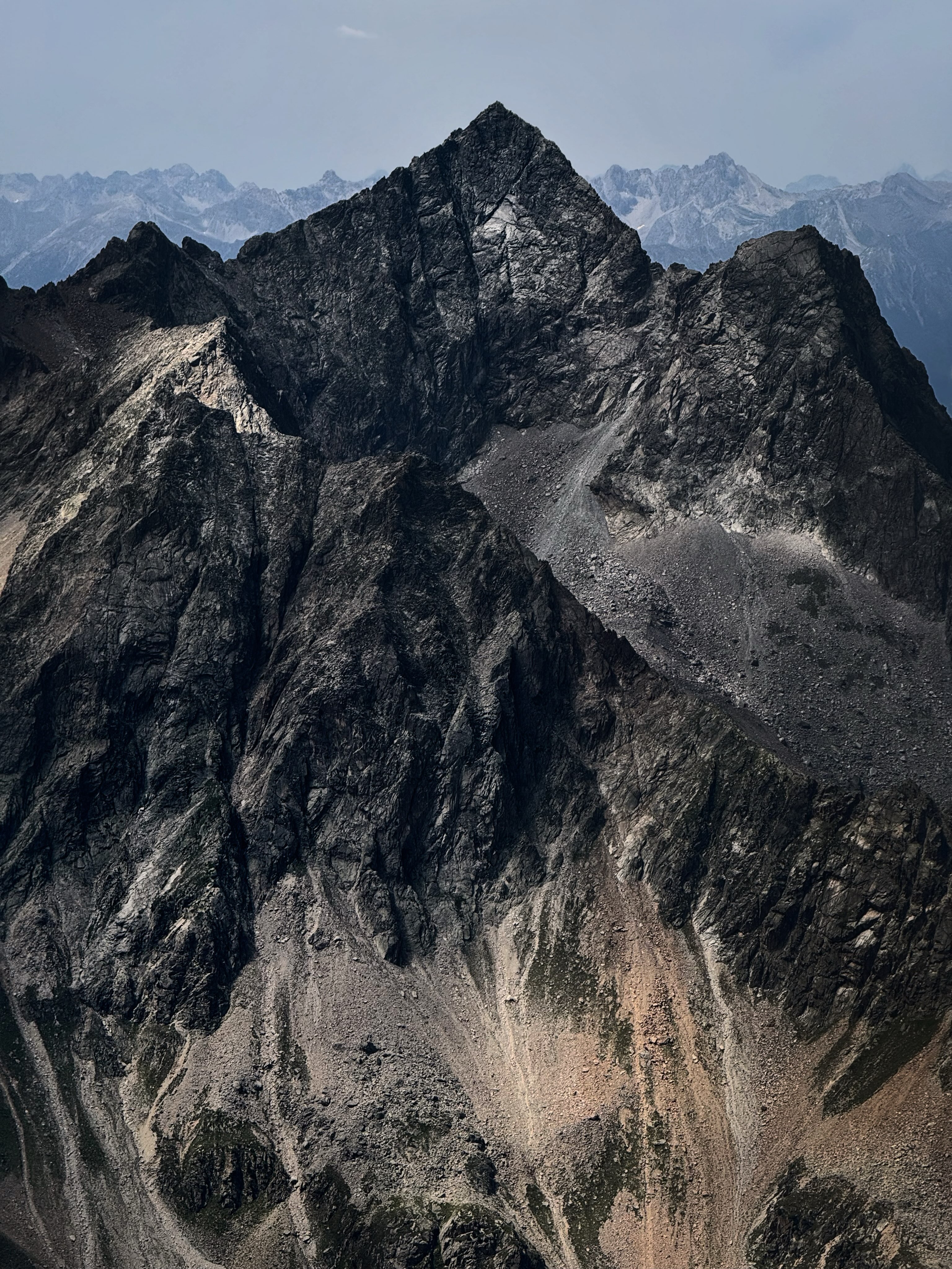 A grey granite peak with snow held in its gullies
