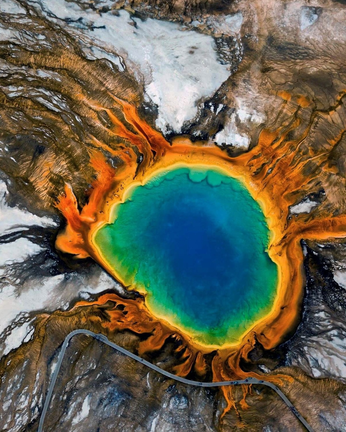 Aerial view of the Grand Prismatic hot spring, orange rim around blue water