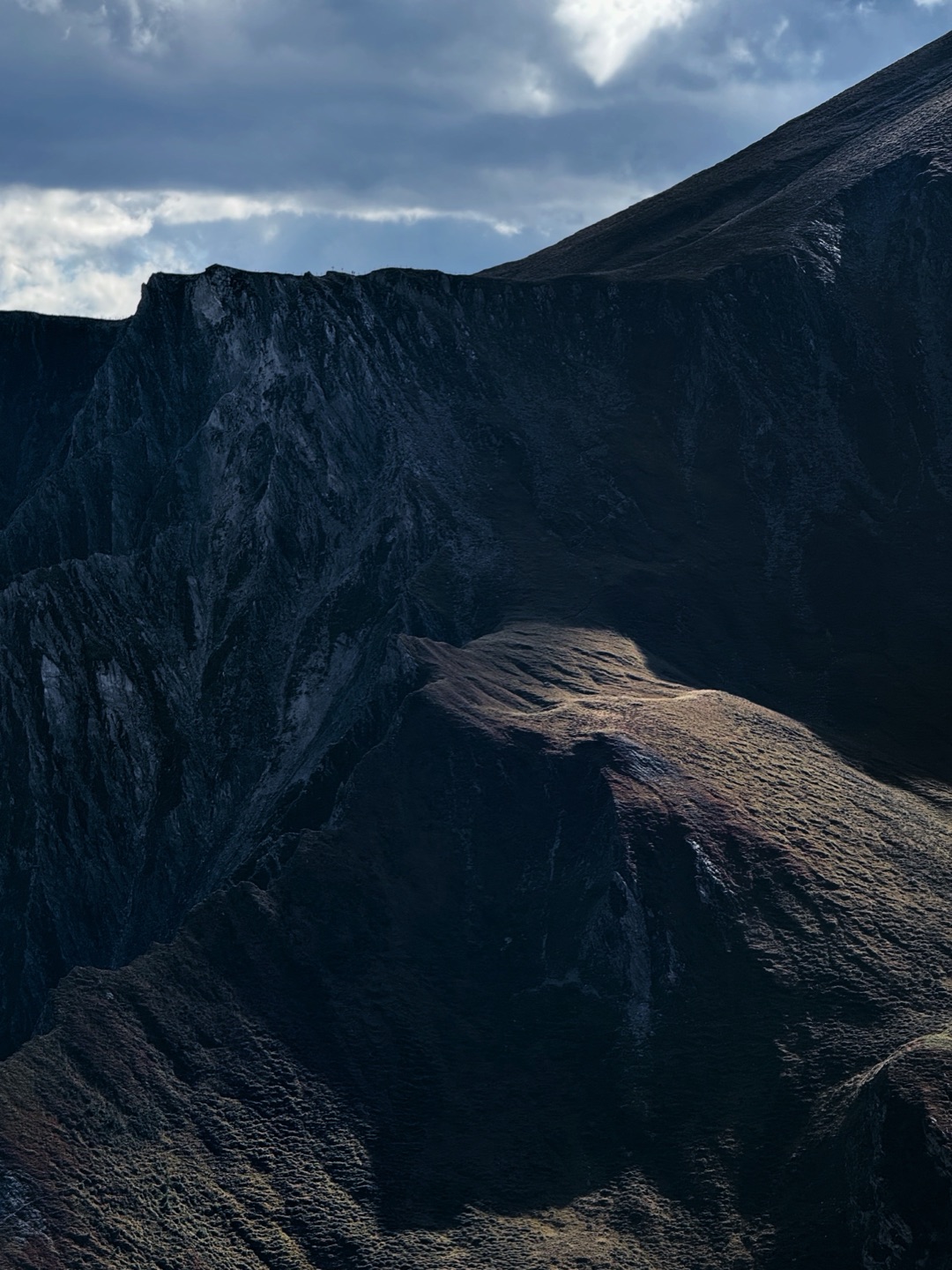 A jagged ridge held in shadow, low sun catching the spur below it